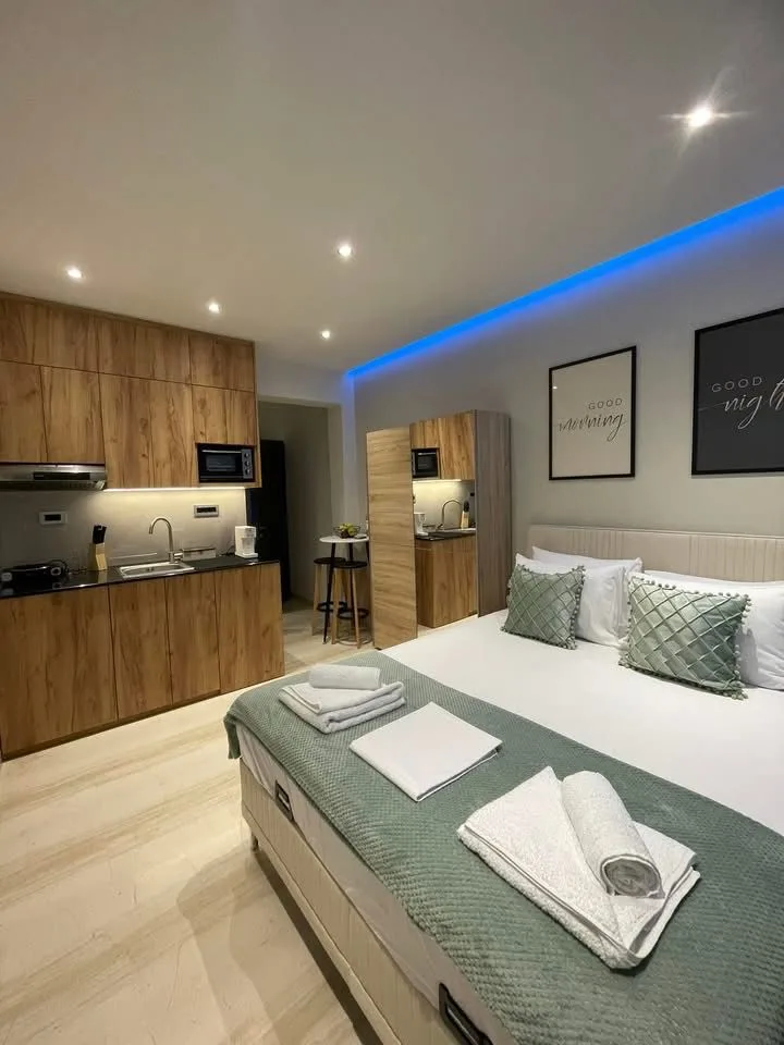 Room One double bed with kitchenette and warm wood finishes